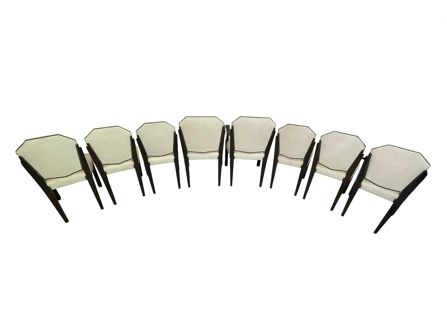 Rear angled view of a vintage set of 8 Art Deco style dining chairs with ivory upholstery, dark mahogany frames, and nailhead trim.