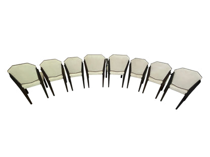 Rear angled view of a vintage set of 8 Art Deco style dining chairs with ivory upholstery, dark mahogany frames, and nailhead trim.