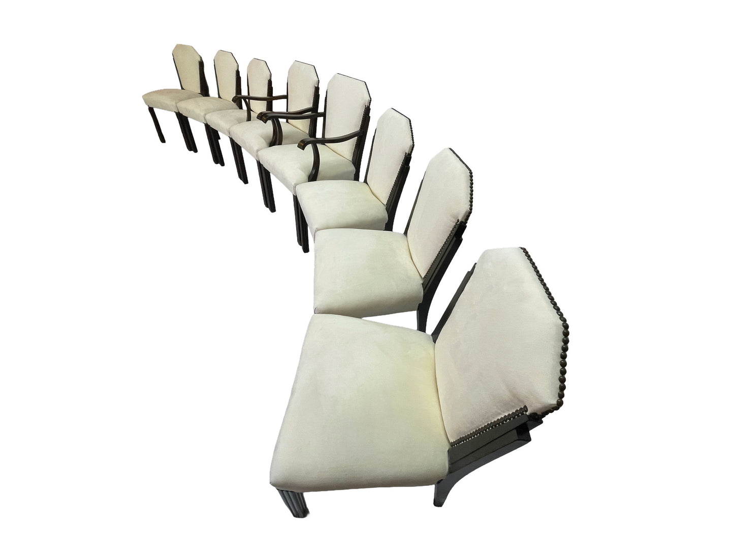 Angled side view of a vintage set of 8 Art Deco style dining chairs with ivory upholstery, nailhead trim, and dark mahogany frames.