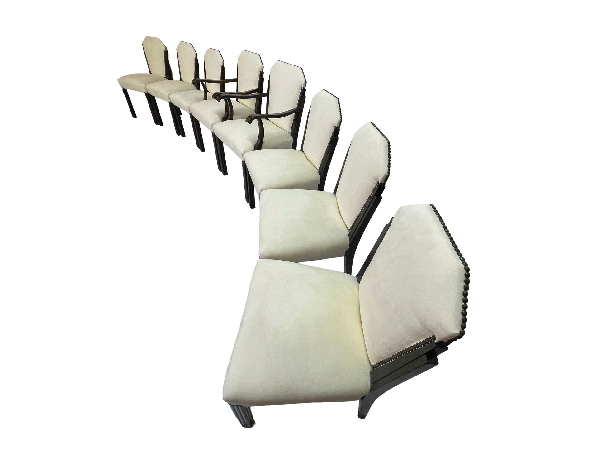 Angled side view of a vintage set of 8 Art Deco style dining chairs with ivory upholstery, nailhead trim, and dark mahogany frames.