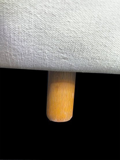 Close-up detail of solid wood cylindrical leg on custom white upholstered contemporary daybed.
