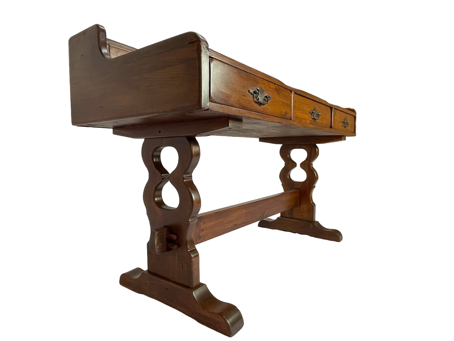 Side three-quarter view of an antique Victorian solid pine writing desk with trestle base and original brass drawer hardware.