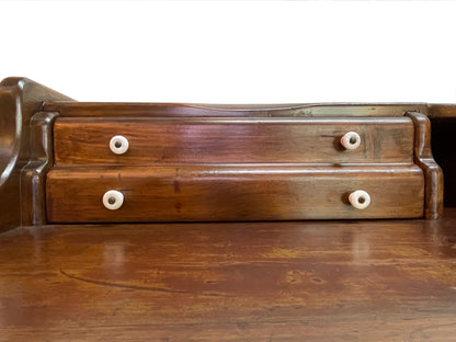 Close-up of original porcelain drawer knobs on an antique Victorian solid pine writing desk with restored finish.