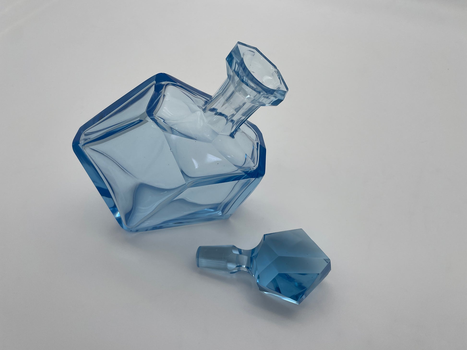 Vintage blue glass decanter shown with its removable faceted glass stopper placed beside the bottle.