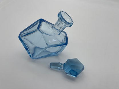 Vintage blue glass decanter shown with its removable faceted glass stopper placed beside the bottle.