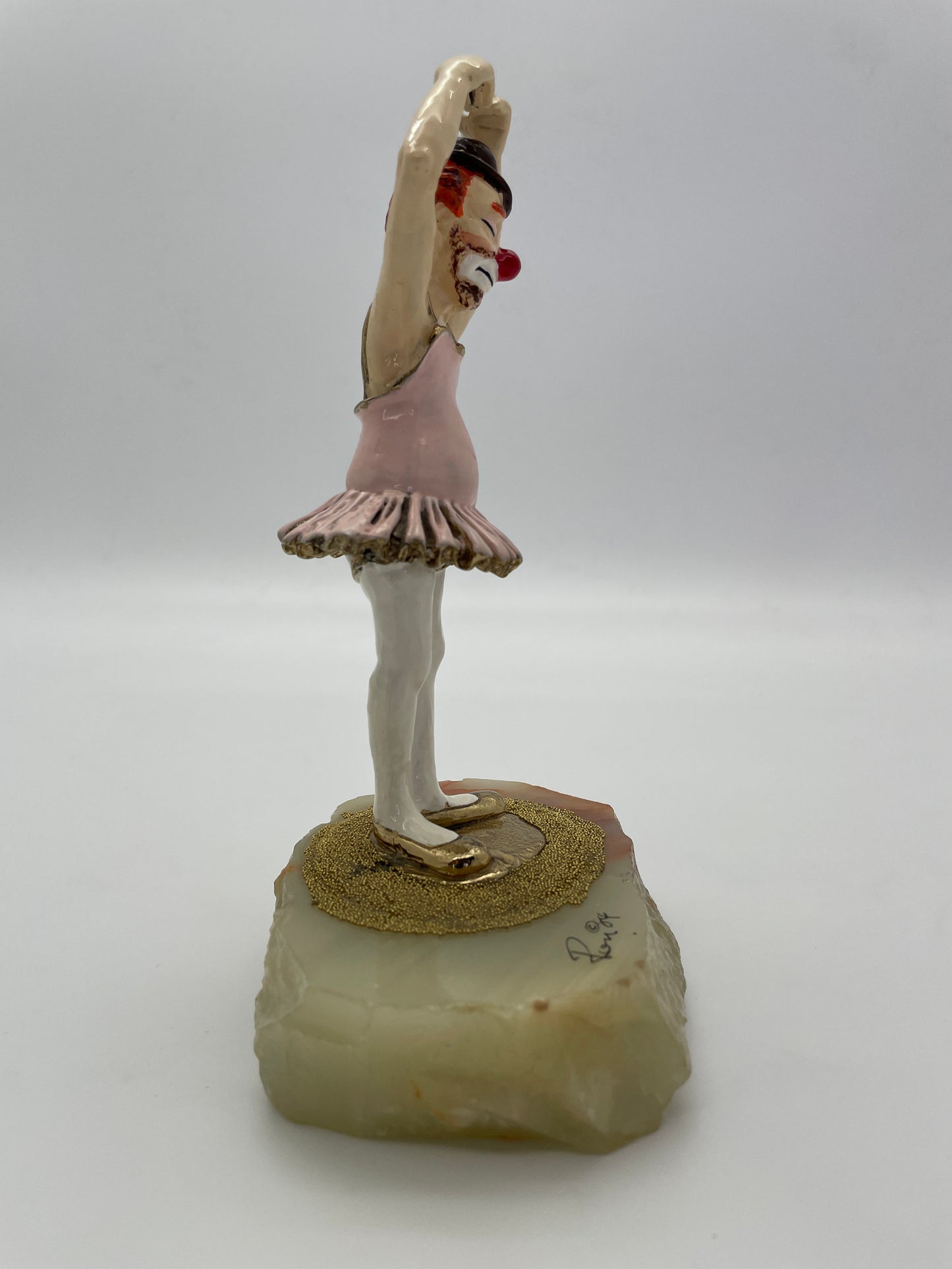 Right side profile of a signed Ron Lee ballet clown sculpture with pink tutu and natural onyx base.