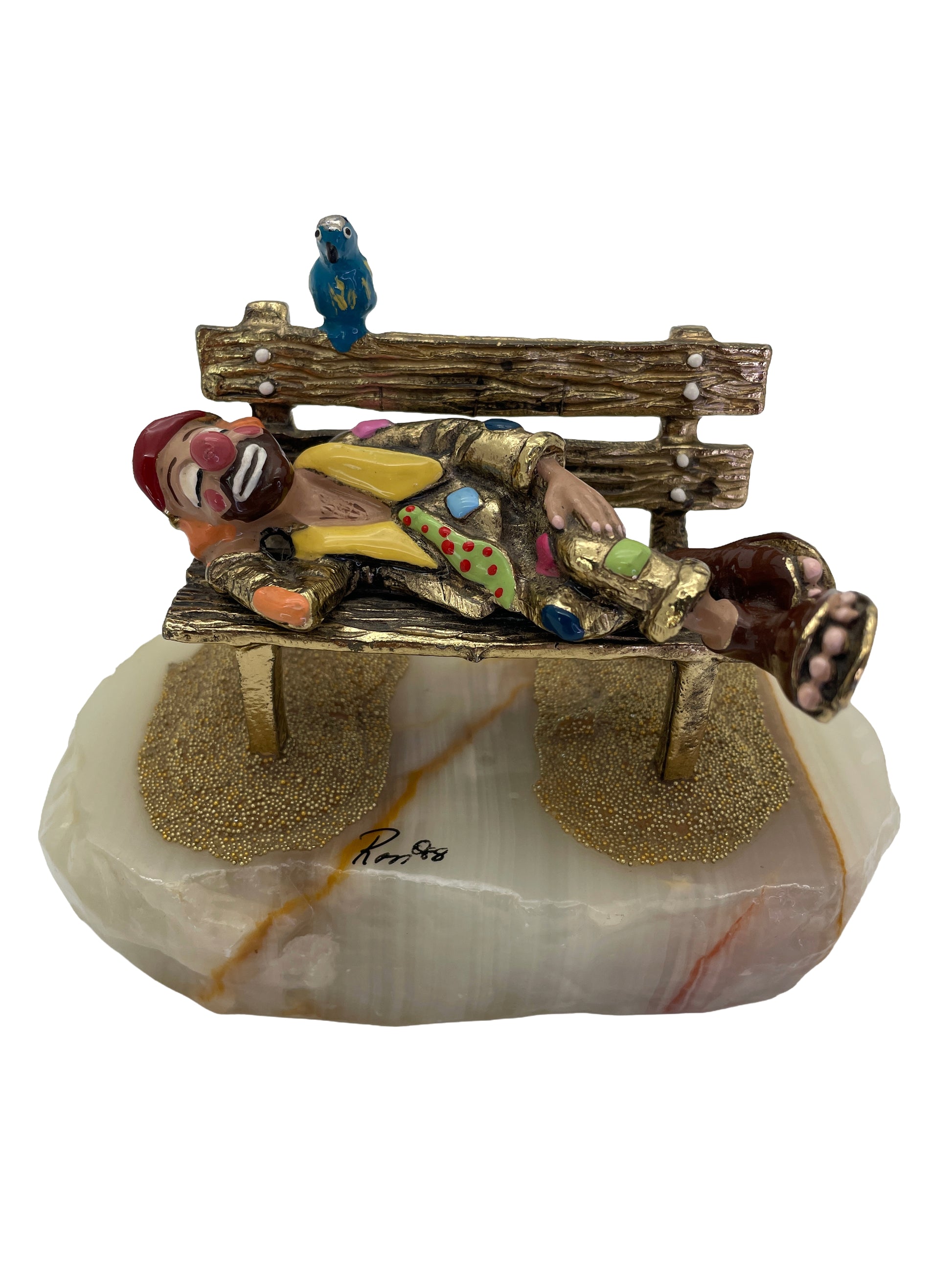 Vintage Ron Lee sleeping clown sculpture resting on a park bench with a blue bird, hand-painted with 24K gold-plated finish on a natural onyx base, signed 1988.
